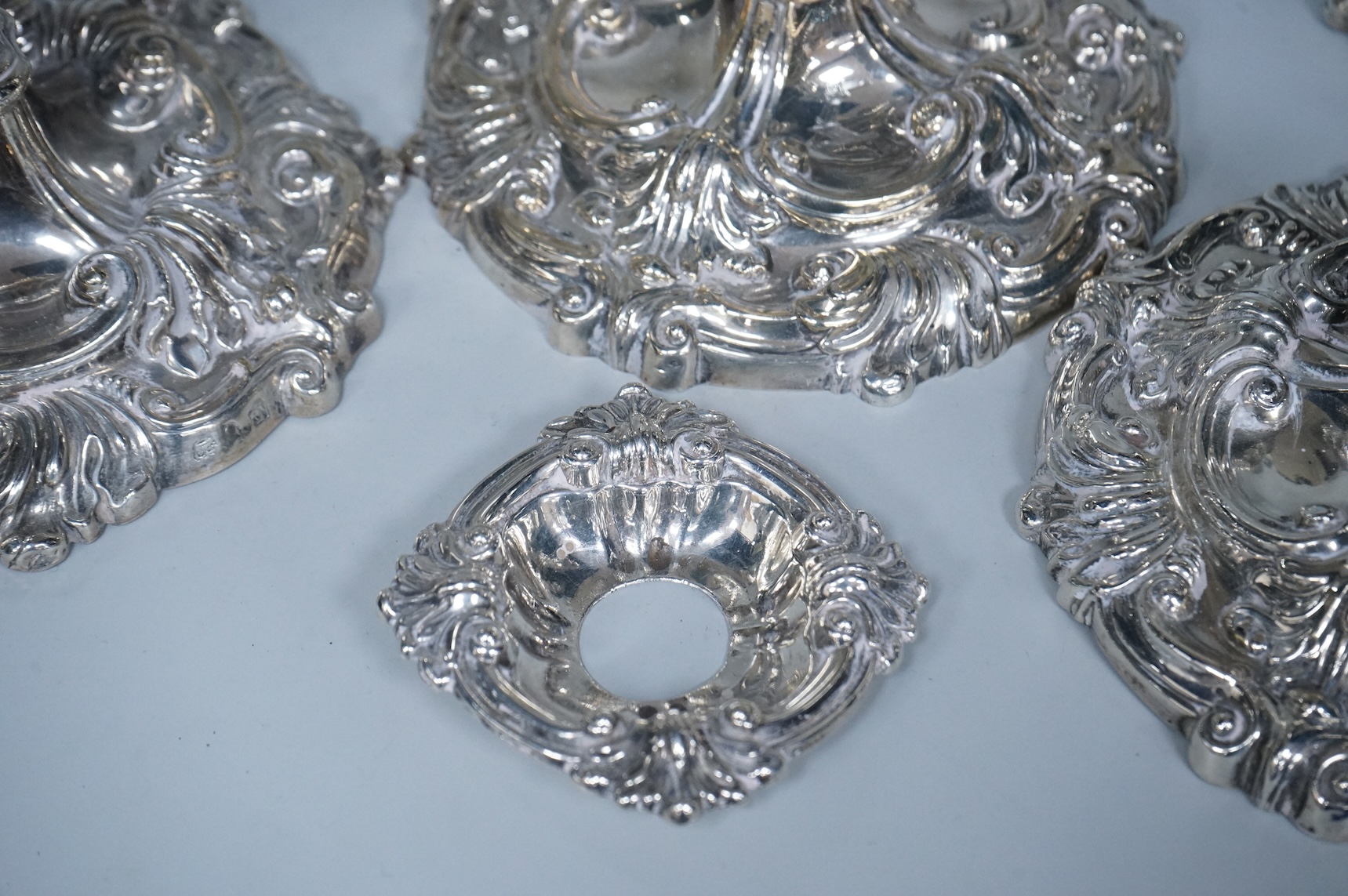 Two similar pairs of George III silver candlesticks, both with fluted tapered columns and decorated with foliage and scrolls, fixed sconces, makers mark rubbed, Sheffield, 1814 and S.C. Younge & Co, Sheffield, 1816, 28.5